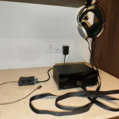 Casque audio suspendu, avec un pré ampli et un ampli audio noirs sur un bureau.