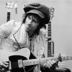 Keith Richards, casquette sur la tête, joue de sa guitare Fender Telecaster, entouré d'autres guitares.