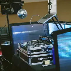 Un booth DJ prêt pour la fête, avec platines, ordinateur portable et boule disco scintillante. L'ambiance est assurée !