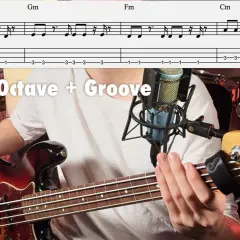 Un musicien joue une ligne de basse sur une guitare basse Fender, avec une partition visible au-dessus.