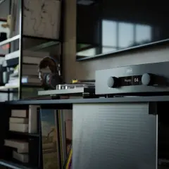 Amplificateur Hegel avec réglage du **damping factor** à 64. Casque et platine vinyle à proximité, dans un salon cosy.