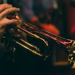 Mains d'un musicien jouant de la trompette, illustrant le fonctionnement de l'instrument.