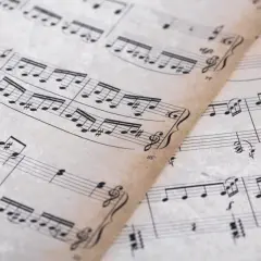 Feuilles de musique anciennes avec des portées et des notes. On y distingue un dessin de clef d'ut.