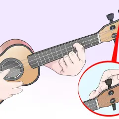 Main d'un musicien ajustant les mécaniques pour l'ukulele accordage. Gros plan sur la tête de l'instrument.