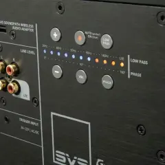 Panneau arrière d'un caisson de basse SVS. Réglage du caisson de basse avec connecteurs RCA, commandes de volume, phase, et indicateurs de fréquence.