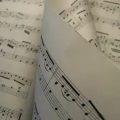 Feuilles de musique aux notes et portées, un dieze sigle se distingue sur une partition pliée.
