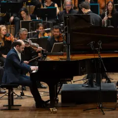 Un pianiste joue un morceau au tempo larghetto, entouré par un orchestre symphonique.