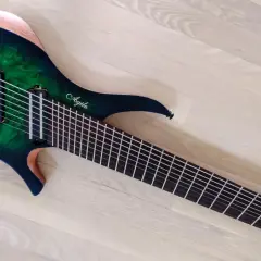 Guitare électrique Agile multiscale vert émeraude, avec 9 cordes et un manche fin, posée sur un parquet clair.