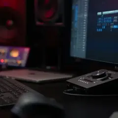 Un setup DJ professionnel avec écran d'ordinateur affichant une table de mixage, des enceintes et une console de contrôle.
