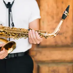 Un musicien tient un saxophone doré, prêt à apprendre cet instrument.