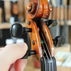 Main d'un musicien ajustant la tension d'une corde pour accorder le violon.