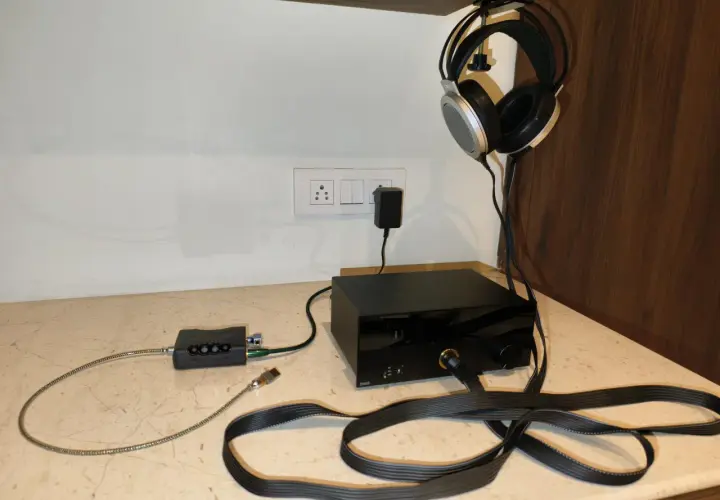 Casque audio suspendu, avec un pré ampli et un ampli audio noirs sur un bureau.