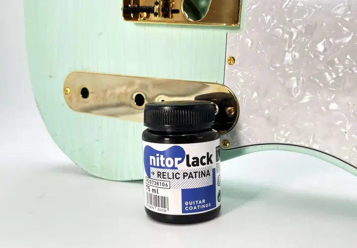 Flacon de "nitorlack relic patina" à côté d'une guitare électrique couleur menthe, prête pour un relicage guitare.