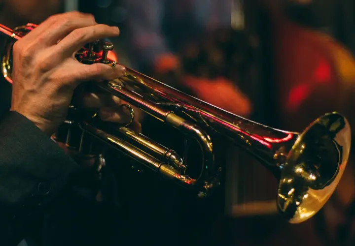 Mains d'un musicien jouant de la trompette, illustrant le fonctionnement de l'instrument.