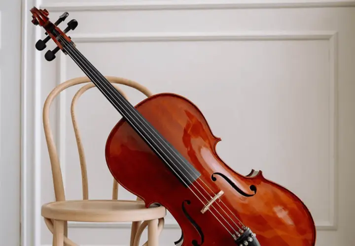 Un magnifique violoncelle en bois verni repose sur une chaise en bois clair, prêt à faire vibrer ses cordes.