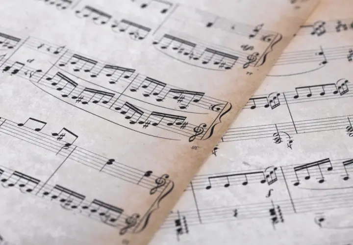 Feuilles de musique anciennes avec des portées et des notes. On y distingue un dessin de clef d'ut.