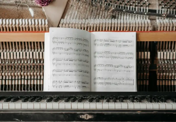 Partition ouverte sur un piano, prête pour un cours de solfège. Les marteaux et les cordes sont visibles derrière la partition.