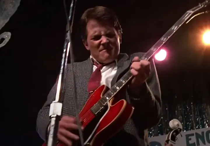 Marty McFly joue de sa guitare rouge emblématique sur scène, prêt à faire vibrer le public.