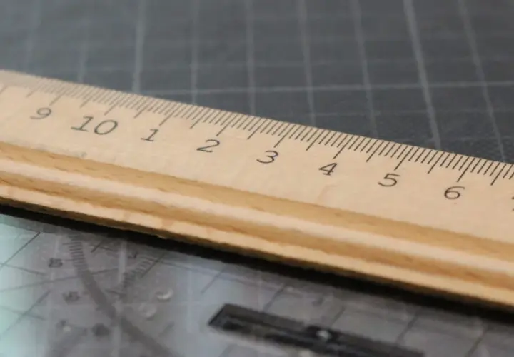 Une règle en bois sur un tapis de découpe, ses graduations formant une signature rythmique parfaite pour mesurer.