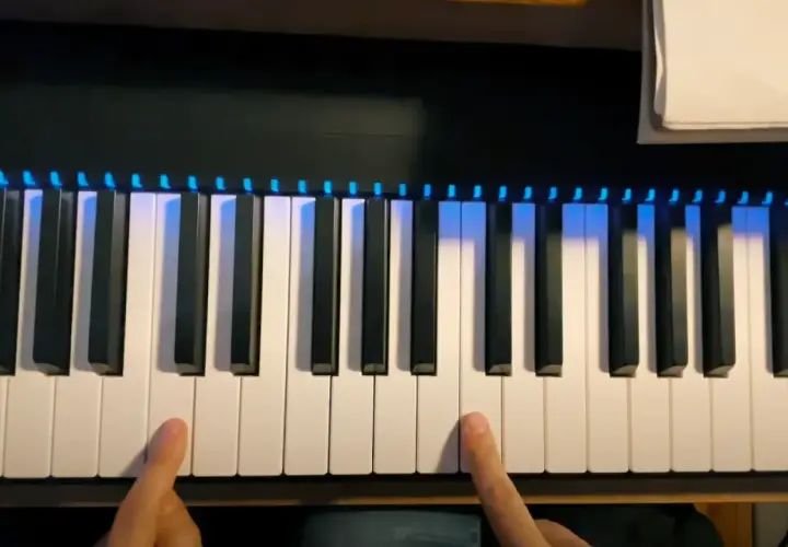 Les doigts effleurent les touches d'un **dièse clavier** illuminé de bleu, prêt à jouer une mélodie.
