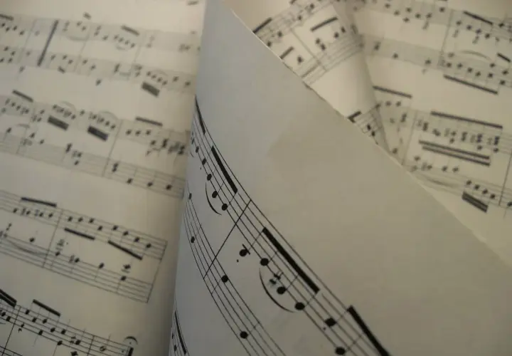 Feuilles de musique aux notes et portées, un dieze sigle se distingue sur une partition pliée.