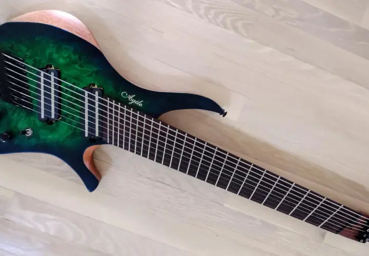 Guitare électrique Agile multiscale vert émeraude, avec 9 cordes et un manche fin, posée sur un parquet clair.