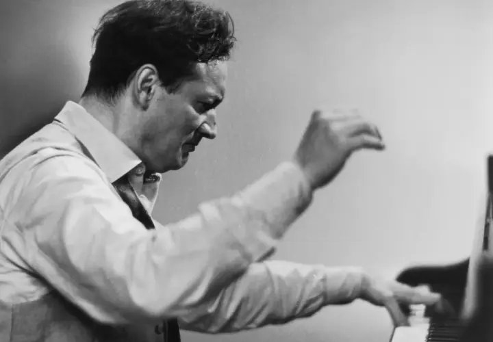 Un pianiste connu, le regard concentré, ses mains effleurent les touches du piano, capturant l'essence de la musique.