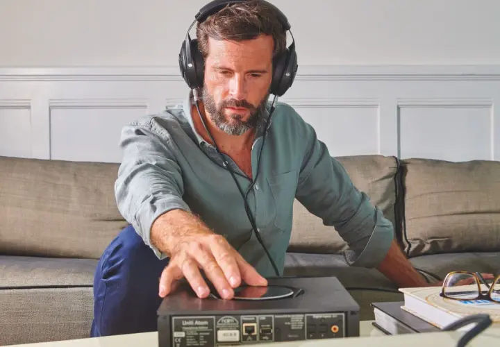 Homme concentré, casque audio sur les oreilles, ajustant un appareil. Il semble tester l'impédance de son casque audio pour une écoute parfaite.