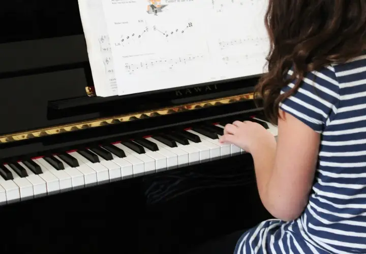 Une jeune fille joue du piano, ses doigts effleurant les touches pour créer une douce mélodie adagio musique.