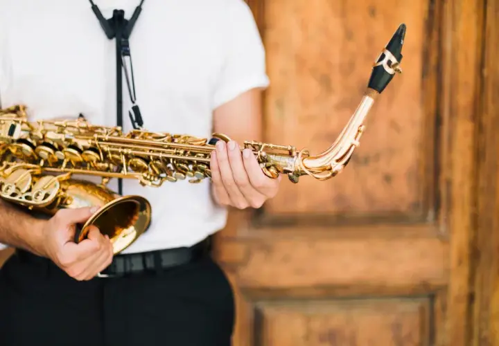 Un musicien tient un saxophone doré, prêt à apprendre cet instrument.