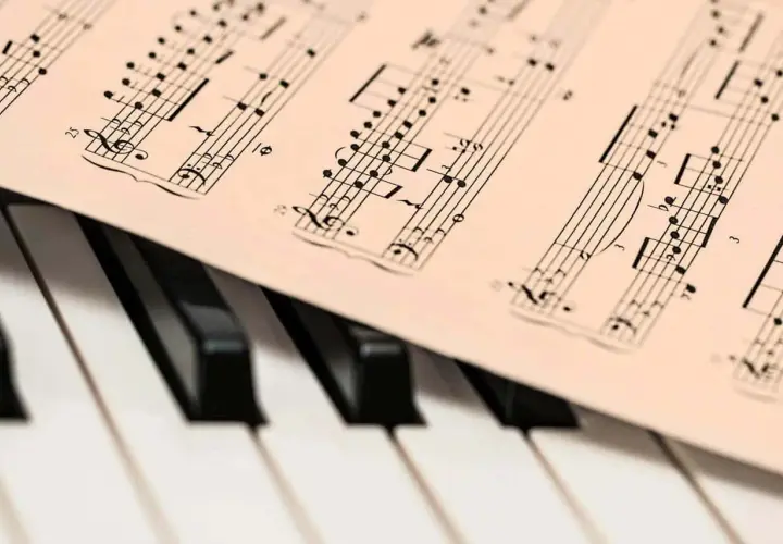 Partition de musique posée sur un clavier de piano. Les notes semblent prêtes à être jouées, une mélodie en attente de la touche de la diese.