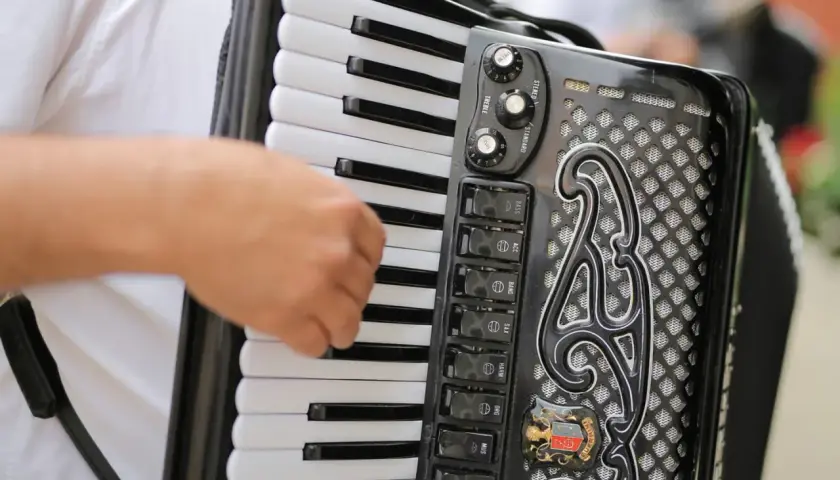 Main d'un musicien jouant sur un accordéon noir, avec ses touches blanches et noires et ses boutons de registres.