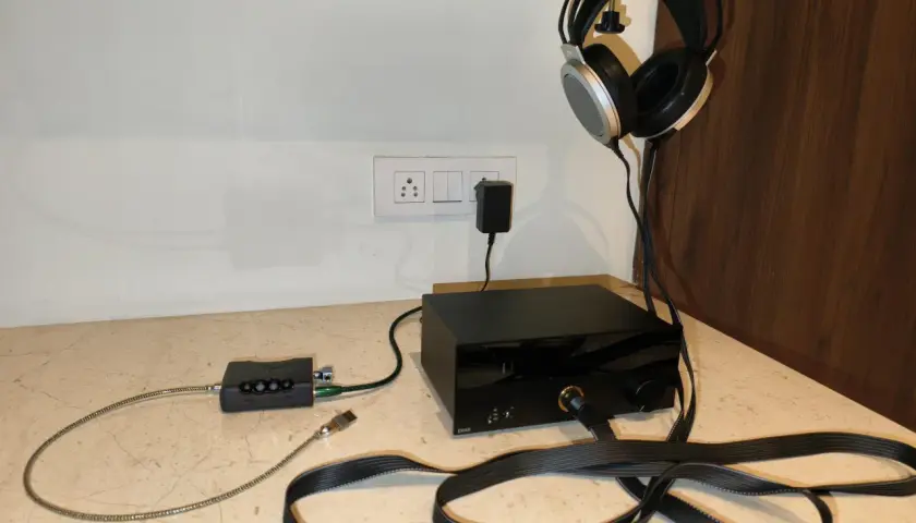 Casque audio suspendu, avec un pré ampli et un ampli audio noirs sur un bureau.