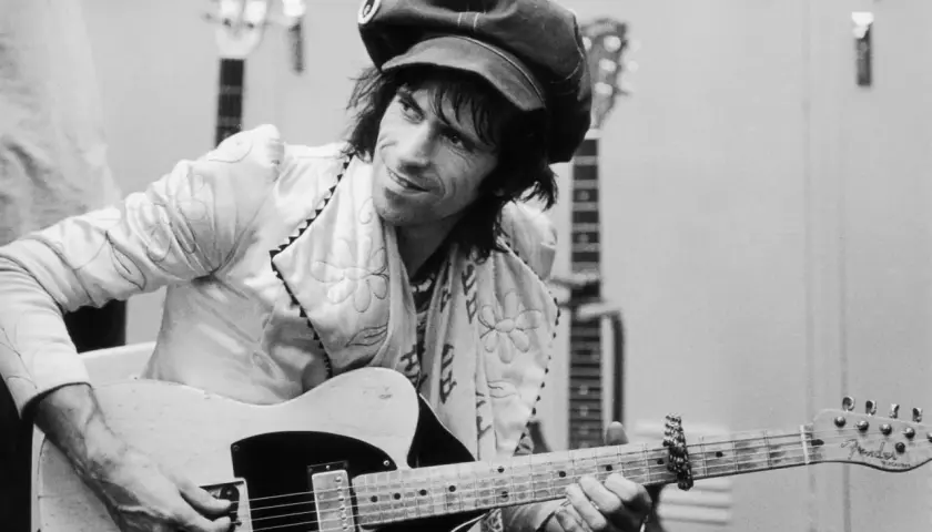 Keith Richards, casquette sur la tête, joue de sa guitare Fender Telecaster, entouré d'autres guitares.