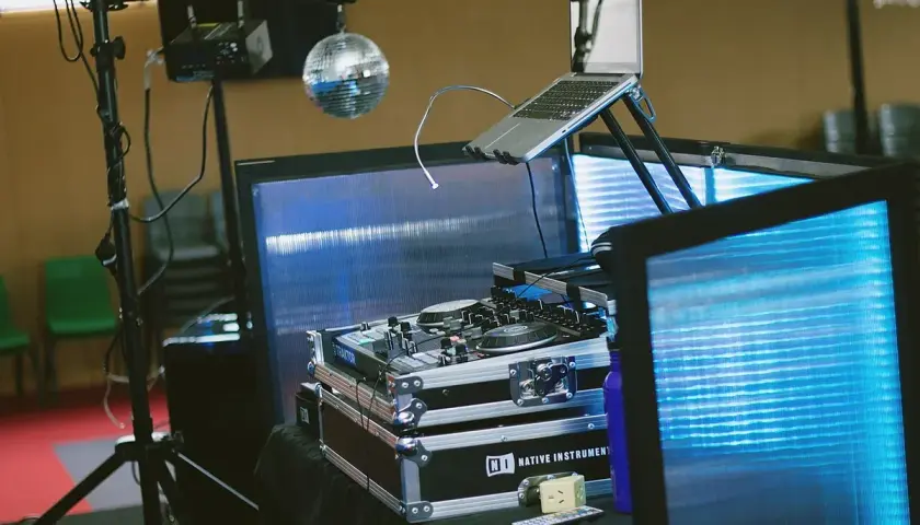 Un booth DJ prêt pour la fête, avec platines, ordinateur portable et boule disco scintillante. L'ambiance est assurée !