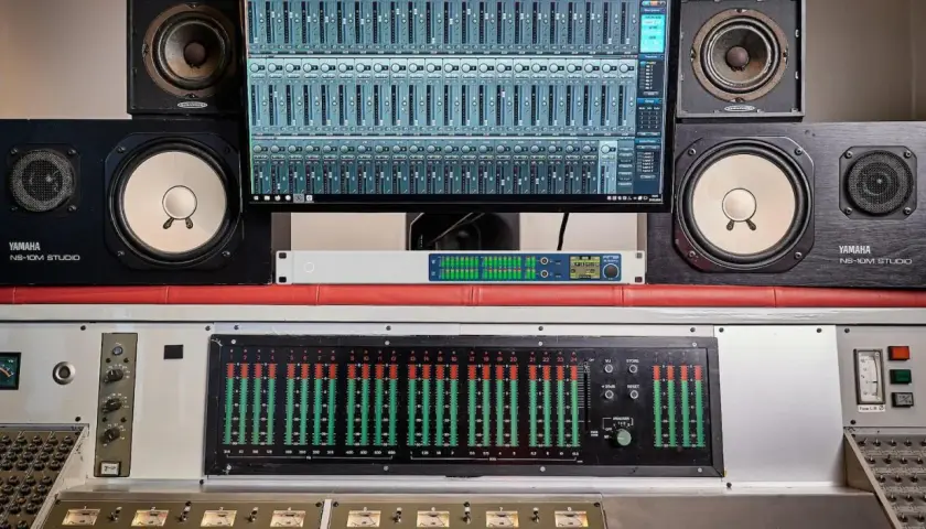 Studio d'enregistrement avec enceintes Yamaha, écran affichant une console numérique et un transducteur sonore.