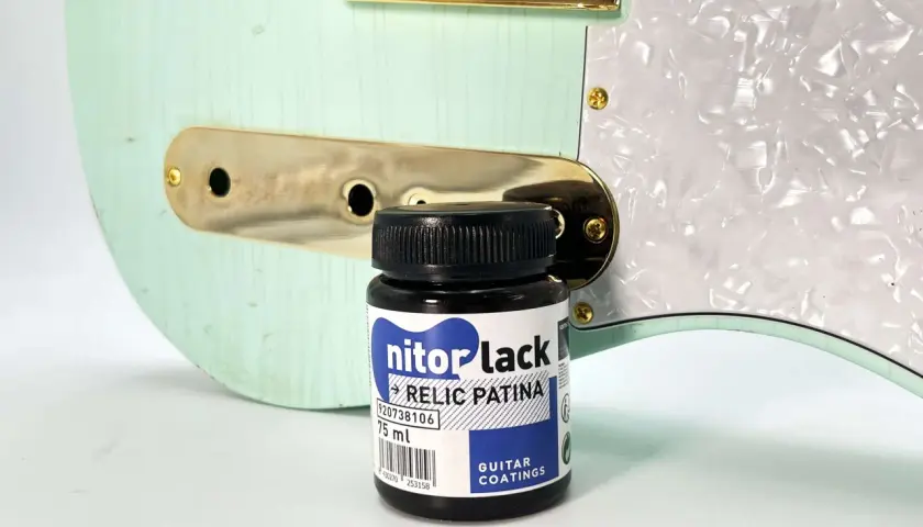 Flacon de "nitorlack relic patina" à côté d'une guitare électrique couleur menthe, prête pour un relicage guitare.