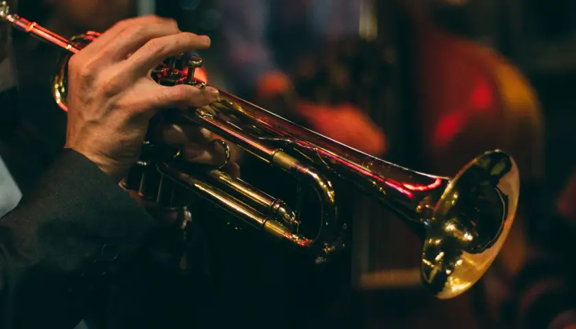 Mains d'un musicien jouant de la trompette, illustrant le fonctionnement de l'instrument.