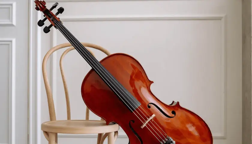 Un magnifique violoncelle en bois verni repose sur une chaise en bois clair, prêt à faire vibrer ses cordes.