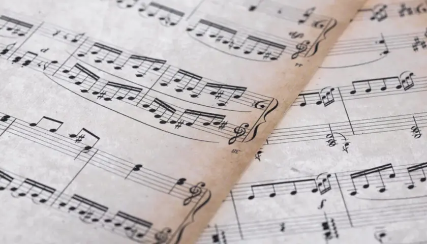 Feuilles de musique anciennes avec des portées et des notes. On y distingue un dessin de clef d'ut.