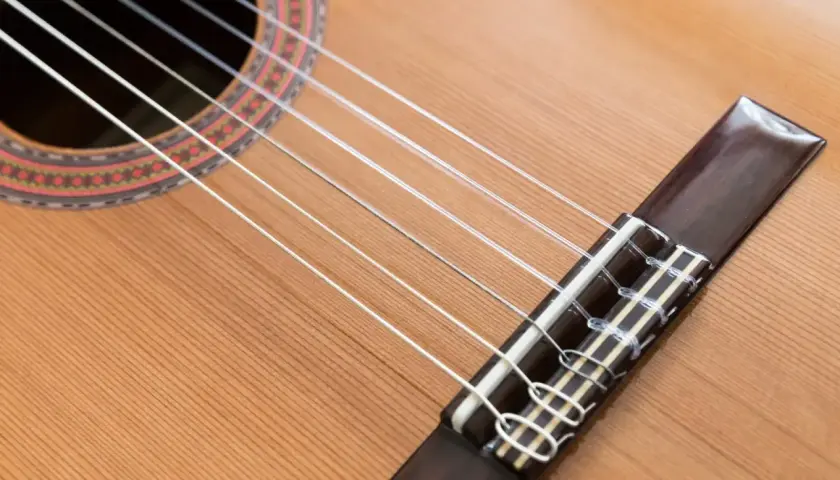 Guitare classique avec ses cordes en nylon, contrastant avec une guitare acoustique. Le bois clair et la rosace ornée invitent à la mélodie.