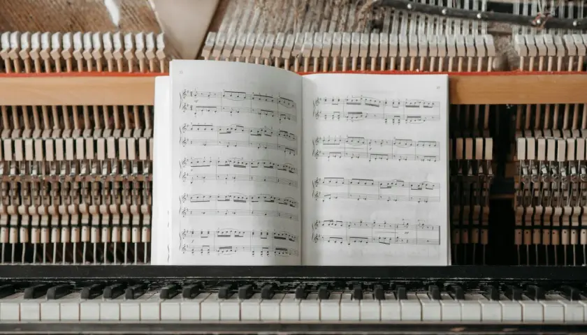Partition ouverte sur un piano, prête pour un cours de solfège. Les marteaux et les cordes sont visibles derrière la partition.