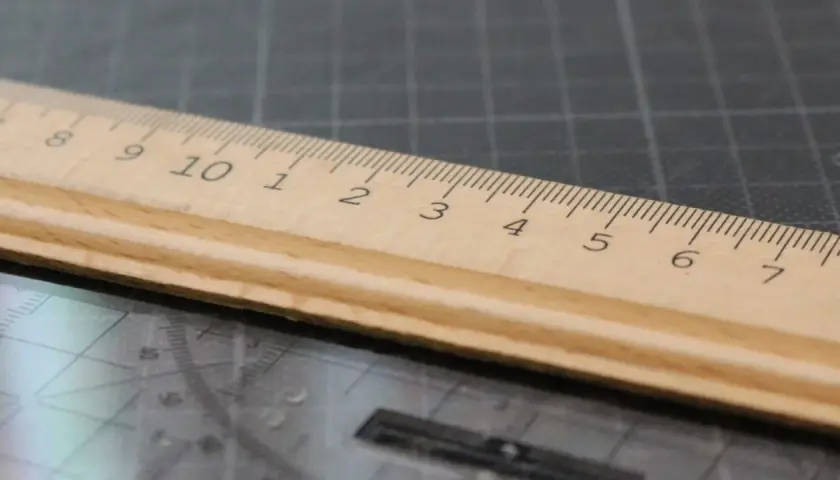 Une règle en bois sur un tapis de découpe, ses graduations formant une signature rythmique parfaite pour mesurer.