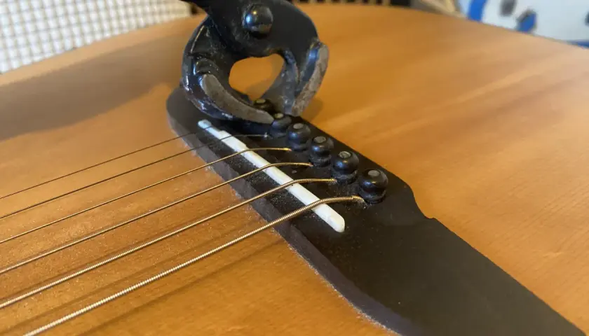 Pince coupante sur le chevalet d'une guitare, illustrant un problème de prise jack.