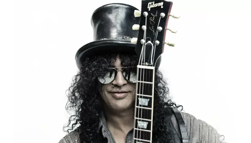 Le guitariste connu Slash, avec son chapeau haut-de-forme et ses lunettes de soleil, tient sa Gibson Les Paul.