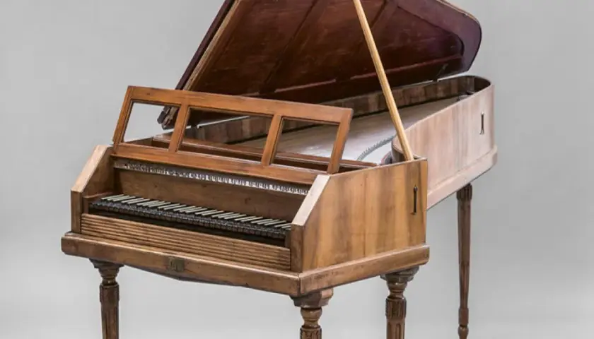 Un clavecin, membre de la famille des instruments à clavier, avec son couvercle ouvert et son pupitre.