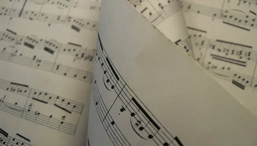Feuilles de musique aux notes et portées, un dieze sigle se distingue sur une partition pliée.