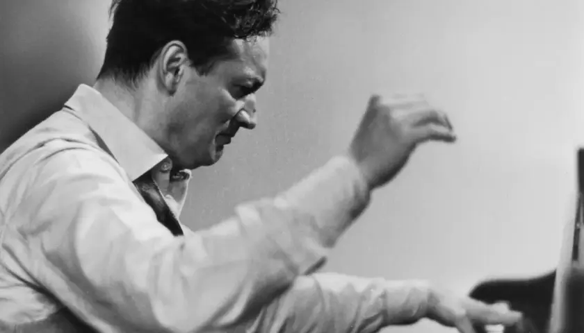 Un pianiste connu, le regard concentré, ses mains effleurent les touches du piano, capturant l'essence de la musique.