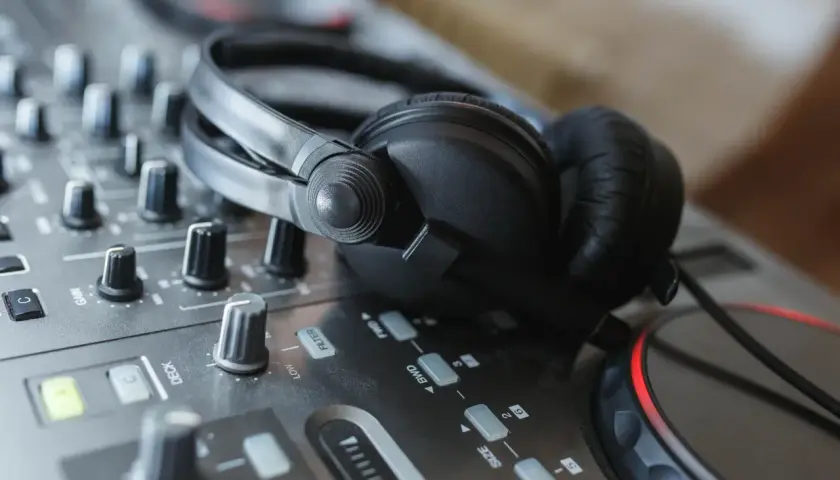 Casque DJ sur une table de mixage, prêt pour le mix. Les boutons et faders, pré et post fader, sont visibles.