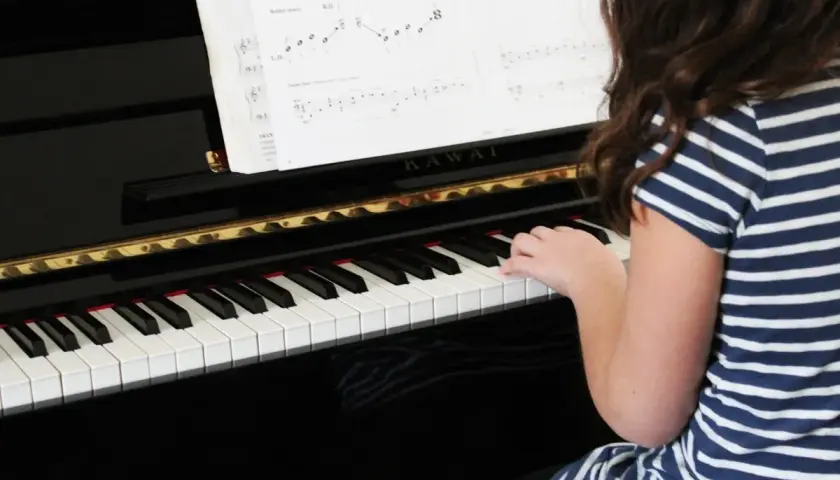 Une jeune fille joue du piano, ses doigts effleurant les touches pour créer une douce mélodie adagio musique.